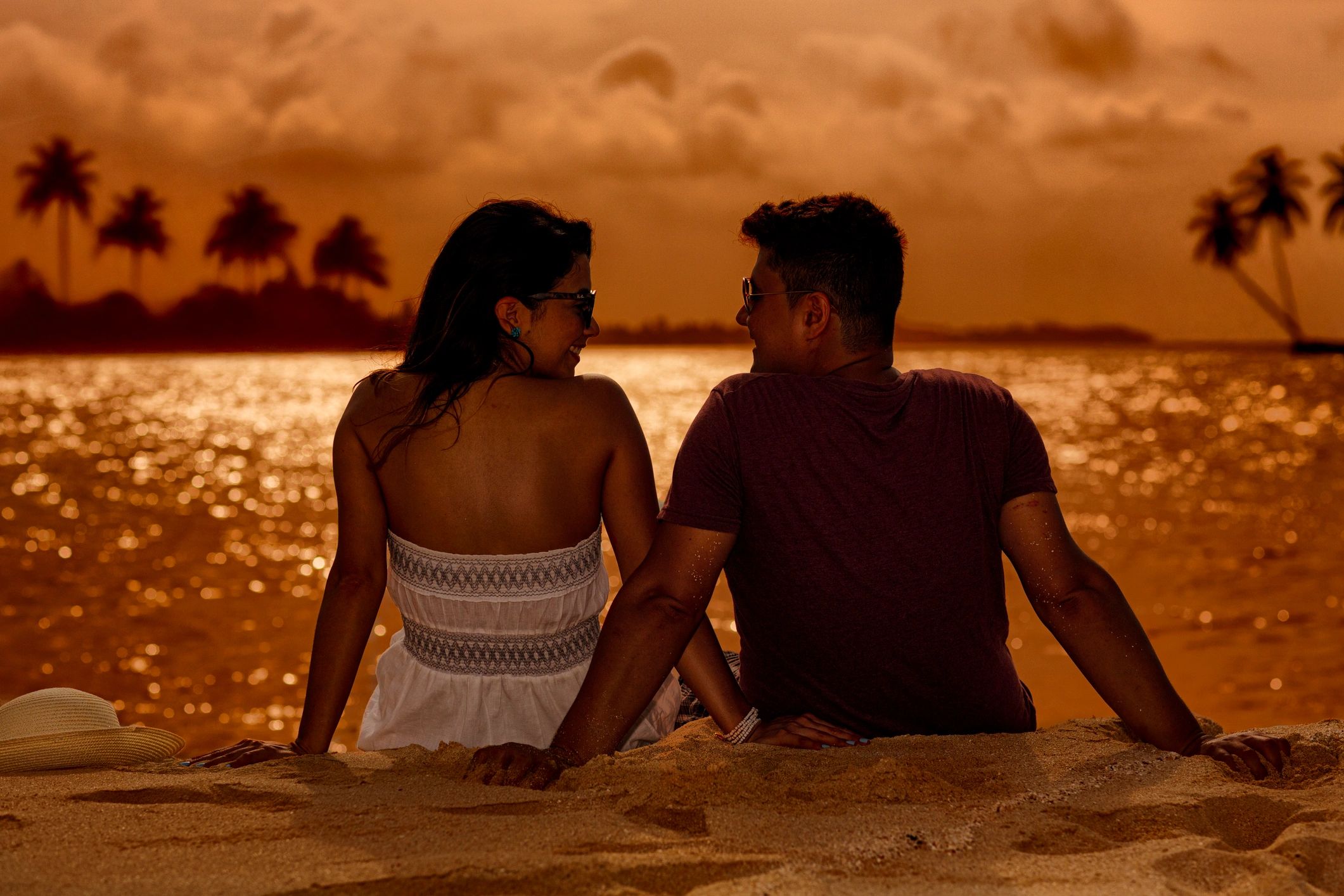 Affectionate couple sitting on the sand at sunset