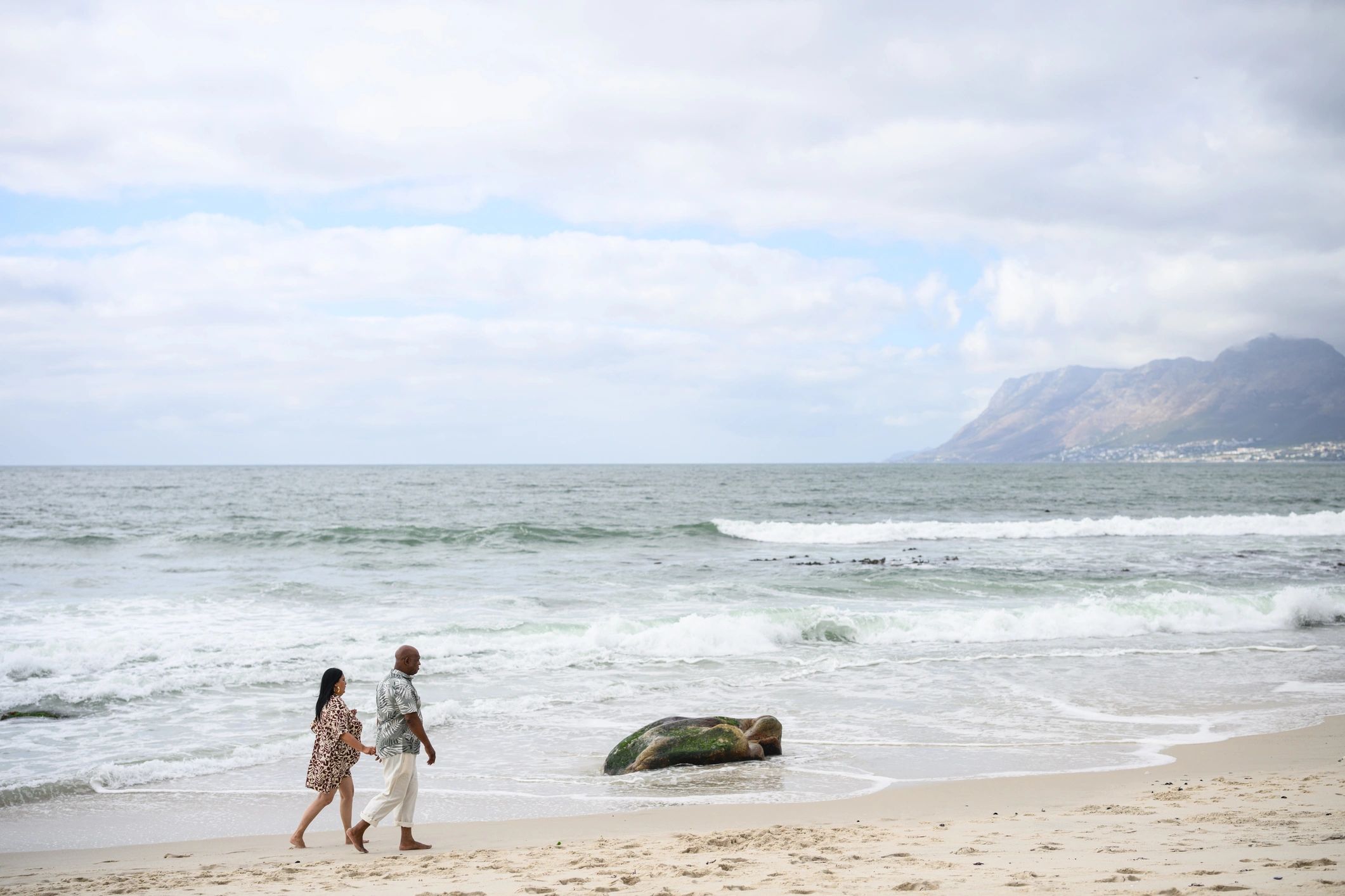 Happy couple walking hand in hand on the beach