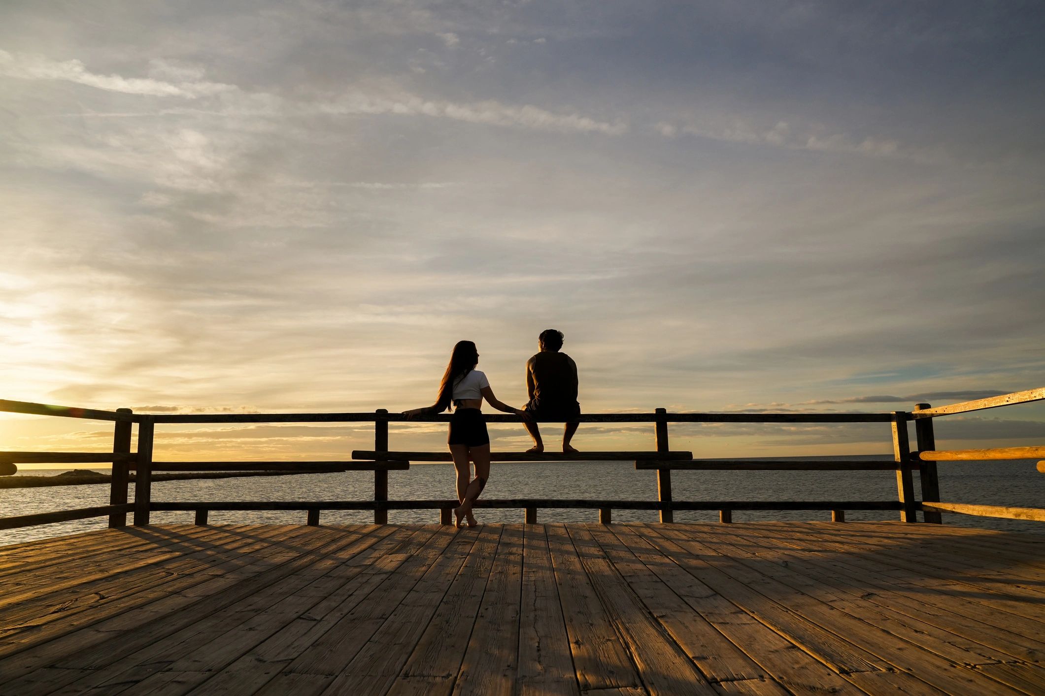 Couple watching the sunset together from a pier